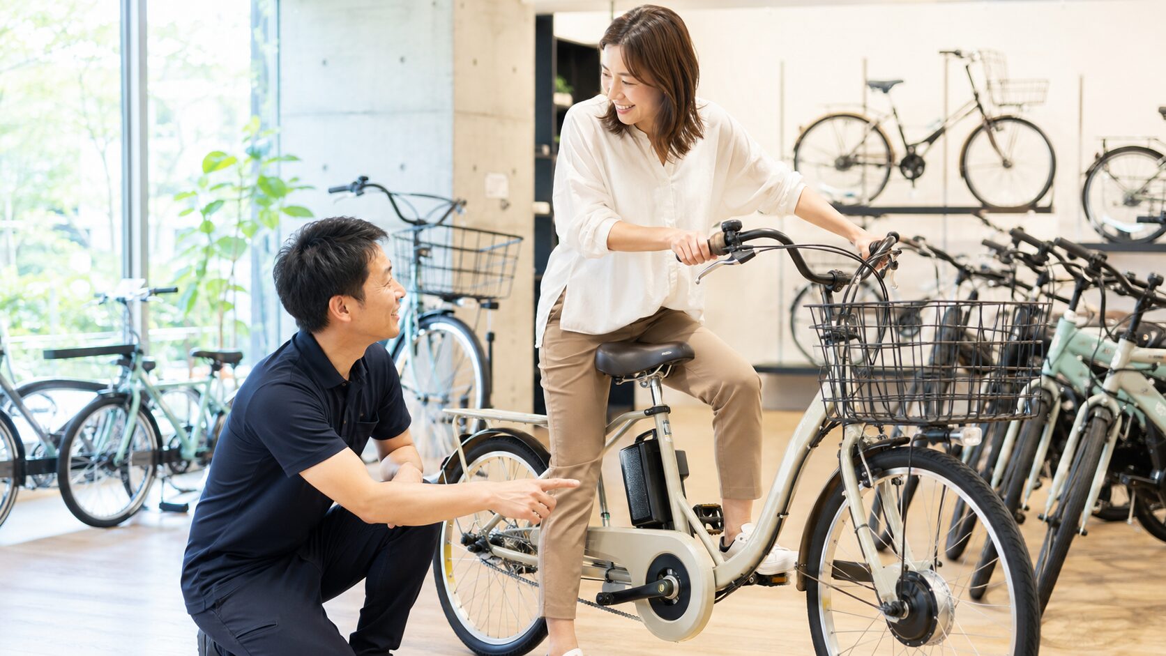自転車店で電動自転車について相談しながら試乗しているイメージ